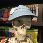 Leo the Skeleton model smiling at the camera, wearing a light blue Tufts Alumni visor, with a button pinned to it of The Block