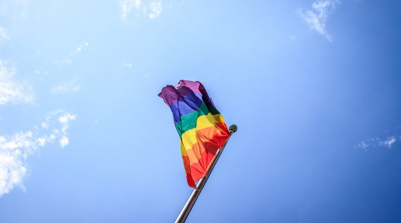 Pride flag against the background of a cloudless blue sky.