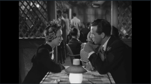 A scene in a black and white film, "Murder, My Sweet." Two characters sit across a table in conversation.