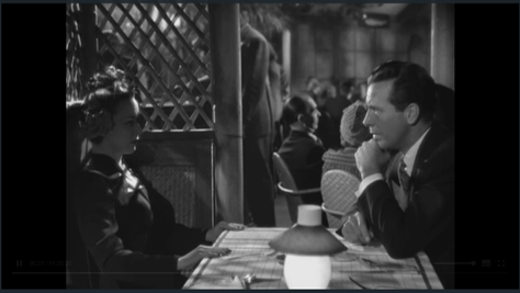 A film noir scene from "Murder, My Sweet." Two characters sit across from one another. The woman on the right is shadowed.