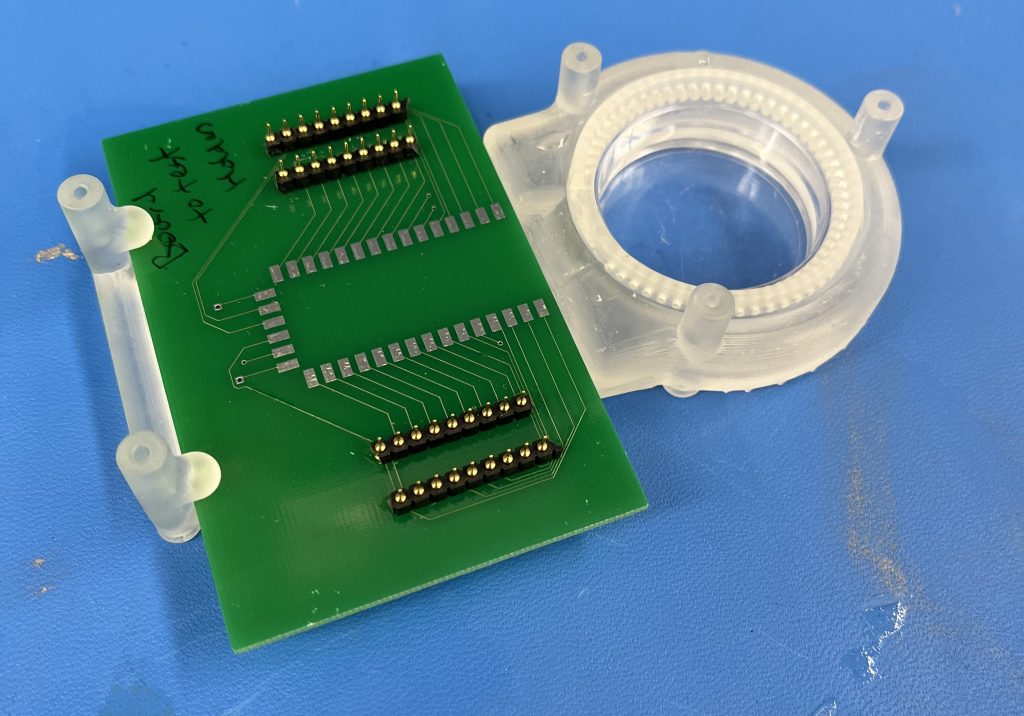 Laboratory image of current design iteration with green MEA resting on chassis. Within the chassis is a larger and removable petri dish holder. 