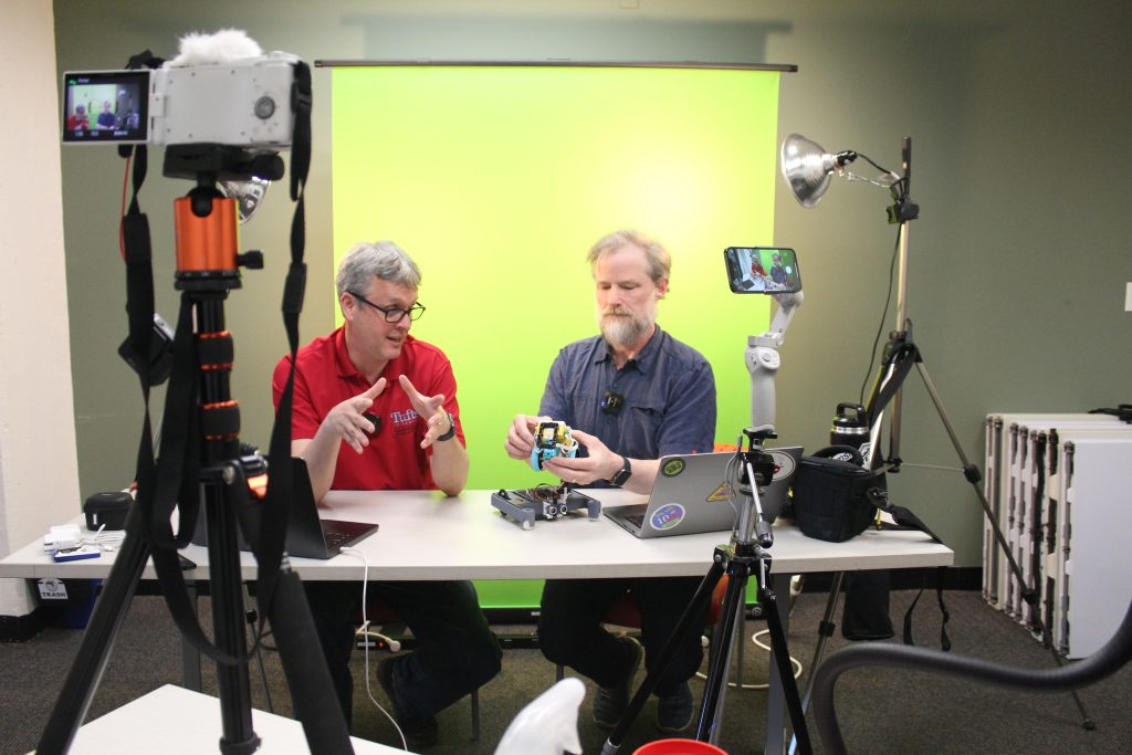 Ethan and Bill in front of a green screen, filming video for online course