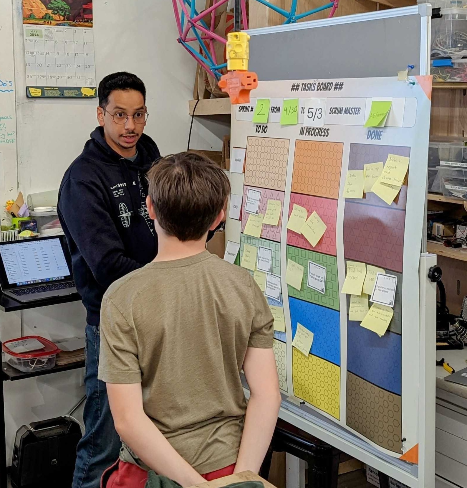 Mohammed talking to student while standing at organizational board