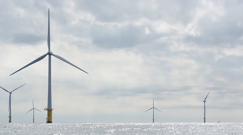 Landscape photo of offshore windmills against a background of clouds