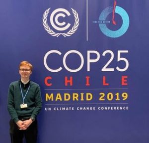 Photo of Asgeir Barlaup in front of a sign reading "COP 25 Chile Madrid 2019"