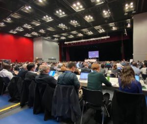 Photo of people sitting down at a conference during a presentation