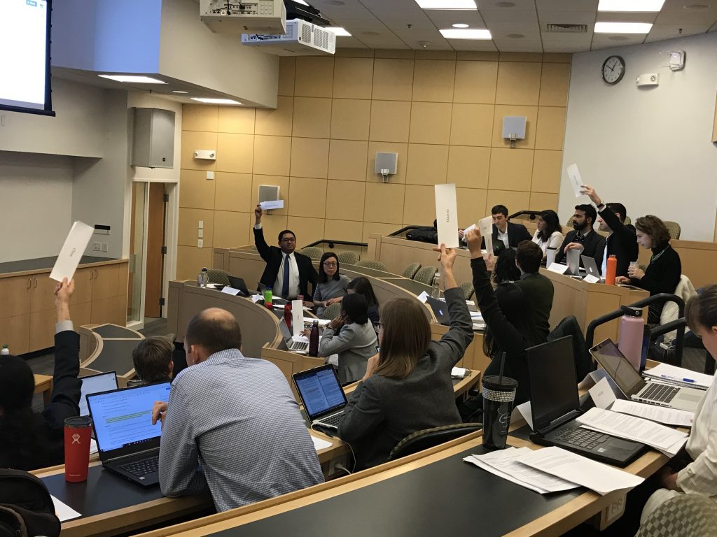 Students seated in a classroom with tiered seating, some holding up cards