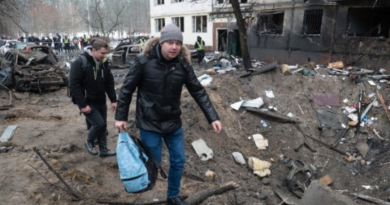 Men walk next to a missile crater in the yard of a high-rise residential building in Dniprovskyi district on December 13, 2023 in Kyiv, Ukraine.