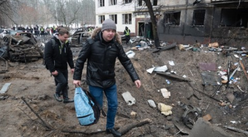 Men walk next to a missile crater in the yard of a high-rise residential building in Dniprovskyi district on December 13, 2023 in Kyiv, Ukraine.