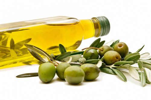 a bottle of olive oil lies on its side next to an olive branch