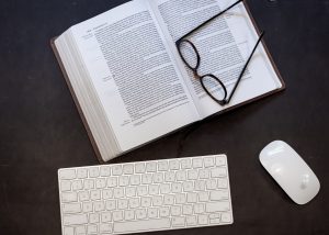 A mouse and computer keyboard, and a book posed in place of a computer screen