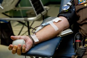 A man's arm in the middle of donating blood, holding a stress ball