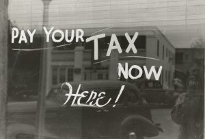 A window with "Pay Your Taxes Here" painted on it.