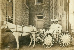 Two Black women pose in horse-drawn buggy decorated with flowers in 1908