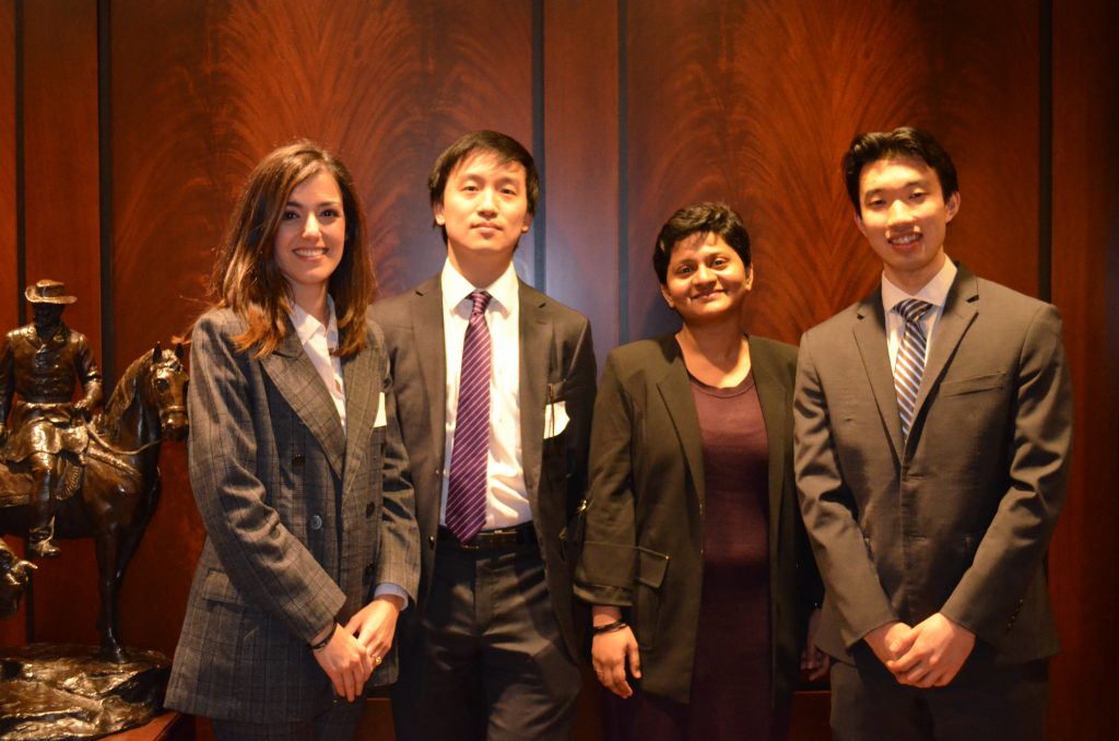 4 young professionals smile and pose for a photograph.