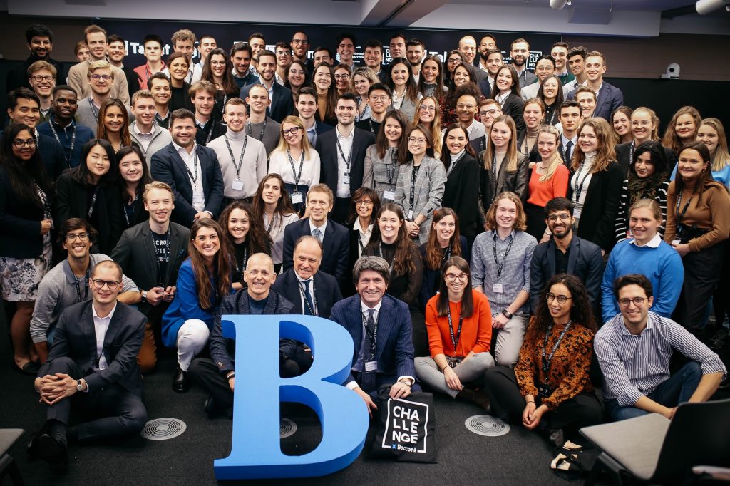 People gather around a big letter "B" placed in the center before them.