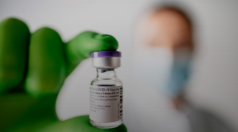 man holds vial of COVID-19 vaccine