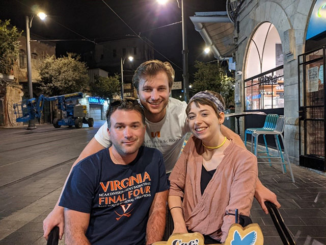 Group of the threee Fletcher School students sitting at an outdoor cafe at night.