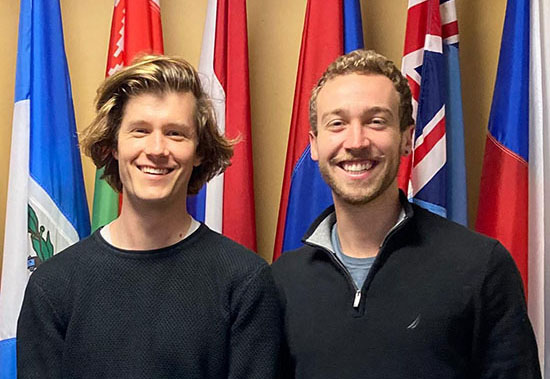 (L-R) Eric Flood, MIB ’22 and David Folsom, MALD ’22. standing in front of several country's flags