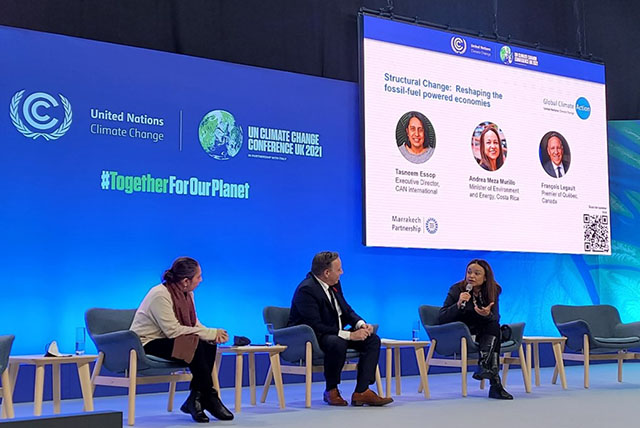 Three panelists on stage sitting in chairs.