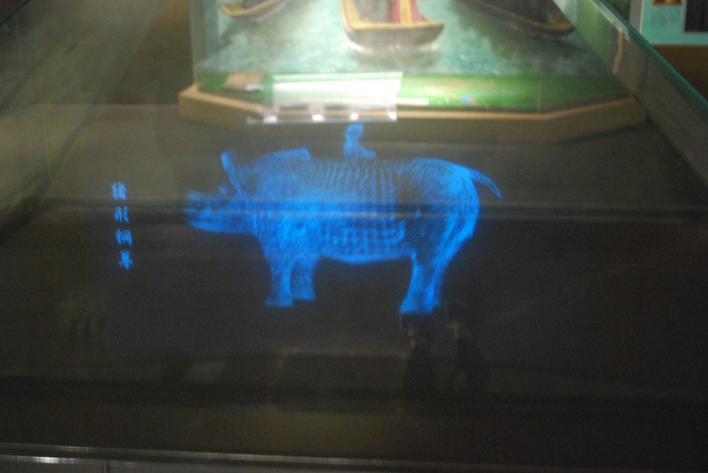 Small projection of a pig statue that rotates for visitors to see all sides of the object. 