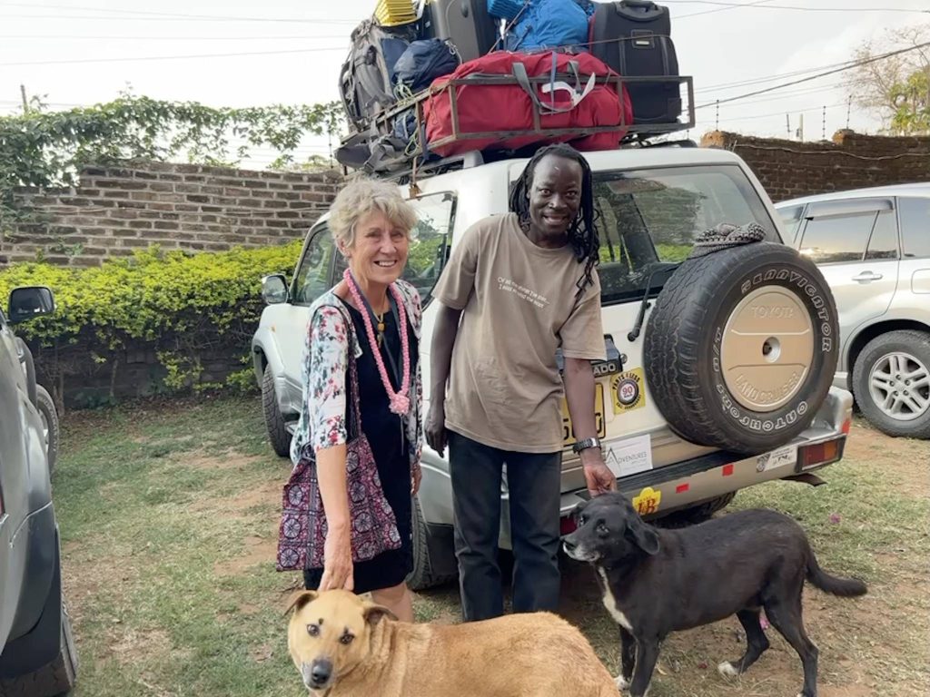 Photo of Sue and Moses during Engineers Without Borders trip with their dogs. Inspiration is behind them, a Toyota land cruiser the travel team and I had driven in during our trip in Malawi.