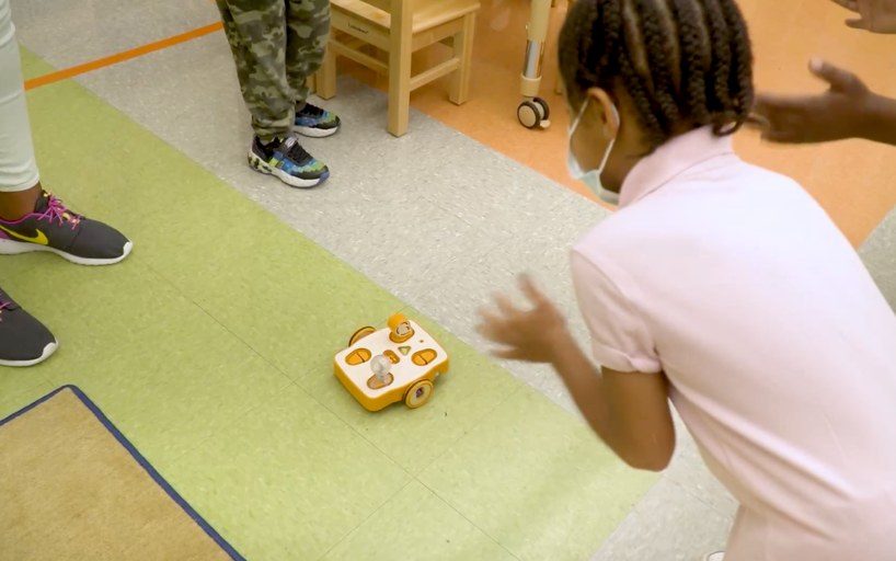 Student clapping at KIBO robot on floor