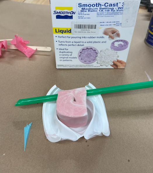 A sacrificial mold made with a yogurt cup. The cup is completely crushed, revealing the hardened Smooth-Sil 940 mold for the wedge.