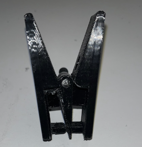 Photographed 3D printed device made of two halves, held together by a screw acting as a hinge. The two halves open and close to apply pressure on a pinch-to-close bag.