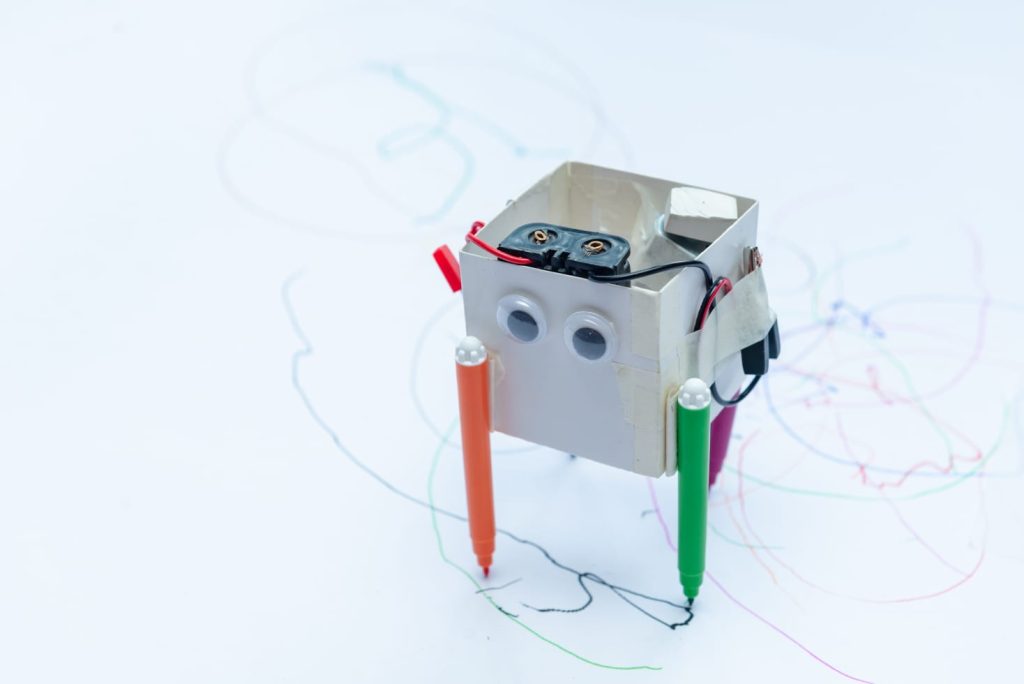 A small robot with pens attached to the bottom to draw