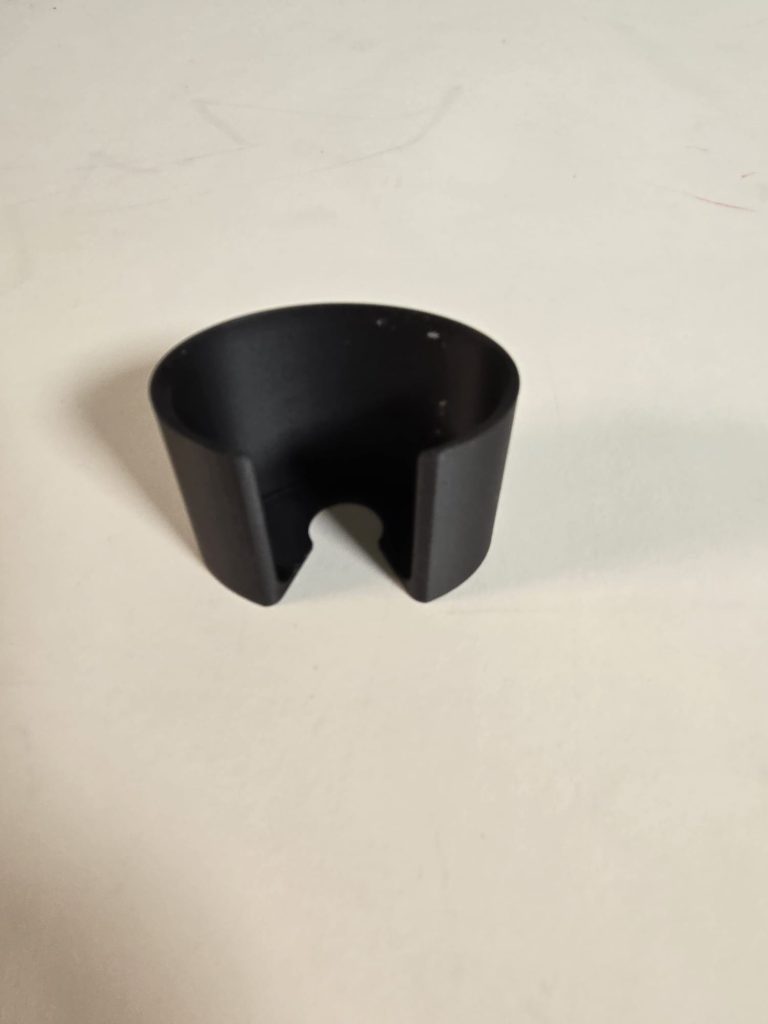 Image shows a 3d printed black open cylinder with a slit.