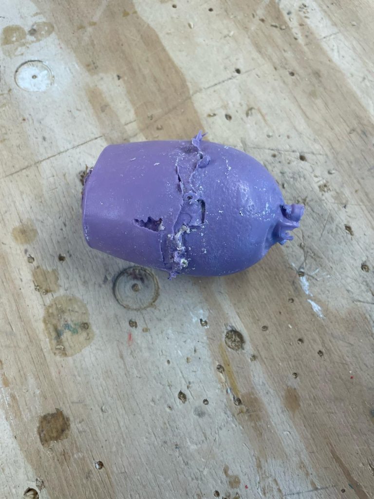 Picture including casted object in purple silicone to the shape of the mold (elliptical shape).