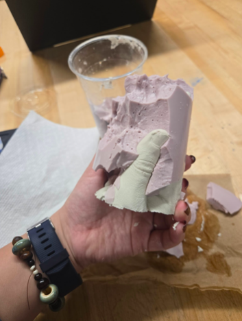 Picture including the casted hand, profile view, still attached to molding material.