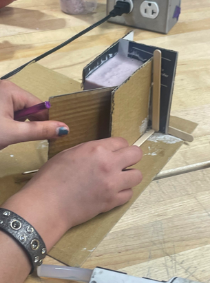 Picture including molding material (alginate) poured in the cardboard box and hands trying to open the box.