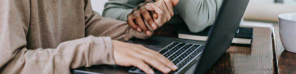 Two people holding hands while one types on a keyboard