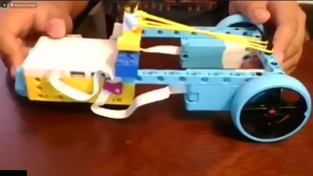 A screen shot from a zoom call in which a student is showing their wheeled device made from a LEGO SPIKE Prime kit. 
