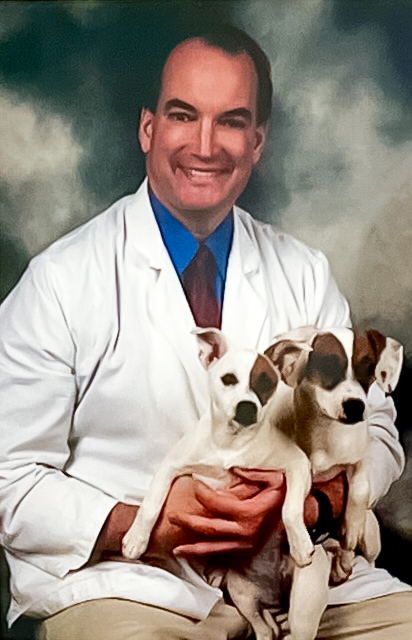 A headshot of Dr. Joseph Kelley, holding two small dogs in his lap.