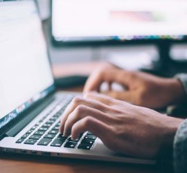 Someone's hands positioned over the keyboard of an Apple MacBook laptop, as if they are typing.