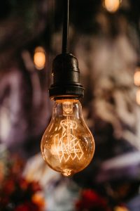 An illuminated Edison-style lightbulb hanging upside down from a cord.