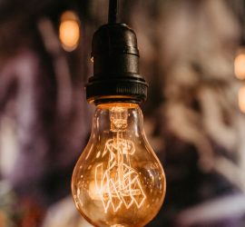 An illuminated Edison-style lightbulb hanging upside down from a cord.